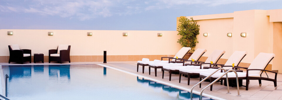 Pool & Sonnenliegen des Avani Deira Dubai Hotel