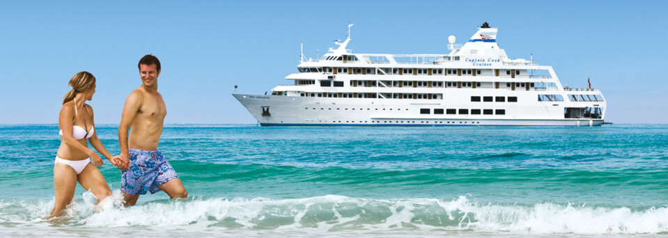 Paar am Strand vor Kreuzfahrtschiff "MV Reef Endeavour" Captain Cook Cruises