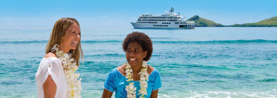 Frauen am Strand vor Kreuzfahrtschiff "MV Reef Endeavour" Captain Cook Cruises
