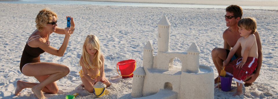 Familie baut Sandburg am Strand von Naples